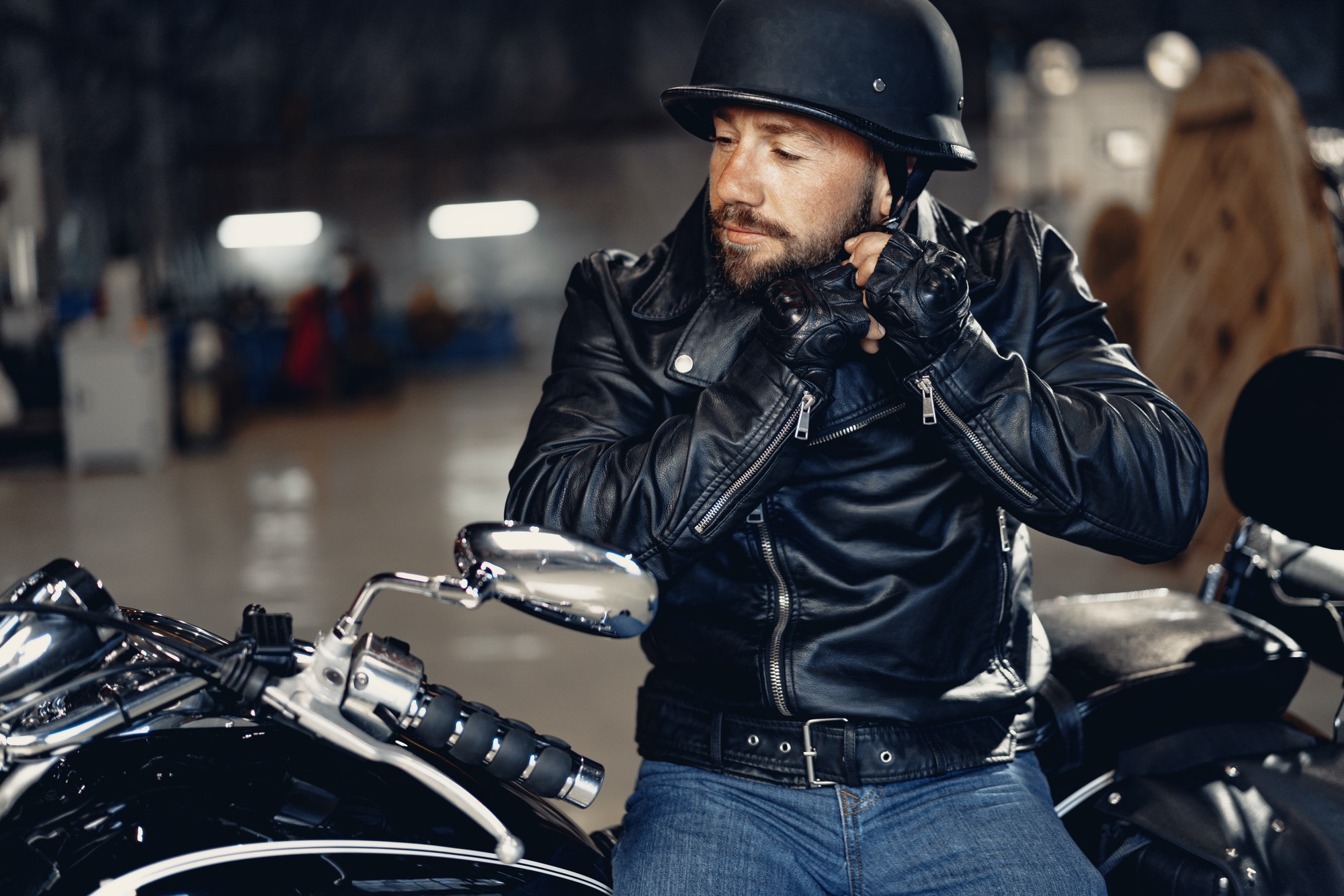 Biker man in leather jacket and helmet sitting on his motorcycle